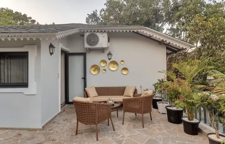 Outdoor seating area with chairs around a table and potted plants towards the side at Lime Tree Villa with Private Pool | Luxury Stay in Goa.